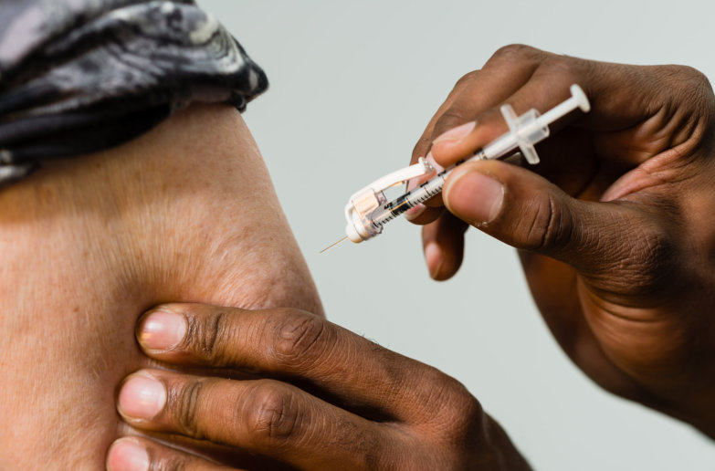 Close up of a syringe about to be injected into a patients arm