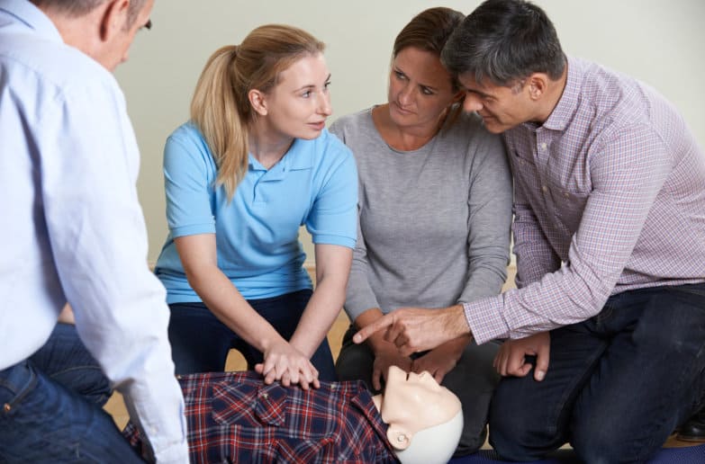 Woman Demonstrates CPR On Training Dummy In First Aid Class